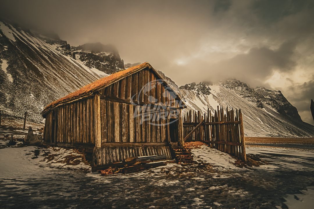Cabaña de madera junto a montañas nevadas