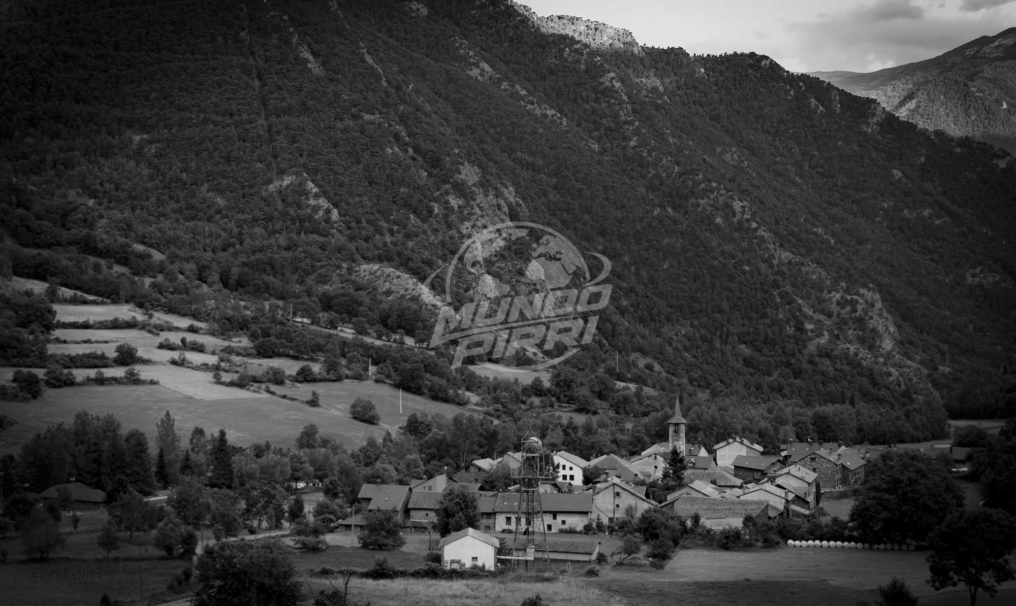 Valle de montaña con pueblo, blanco y negro